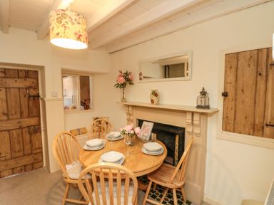 A dining room with a round wooden table set for four near a fireplace at 12 Castlegate in Pickering
