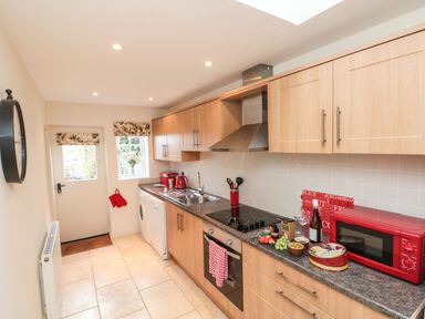 A kitchen with wooden cabinets a red microwave a red kettle and oven at 12 Castlegate in Pickering