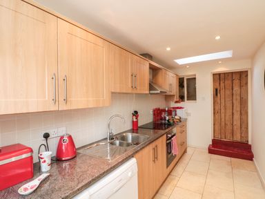 A kitchen with wooden cabinets a double sink red kitchen appliances and a wooden door at 12 Castlegate in Pickering