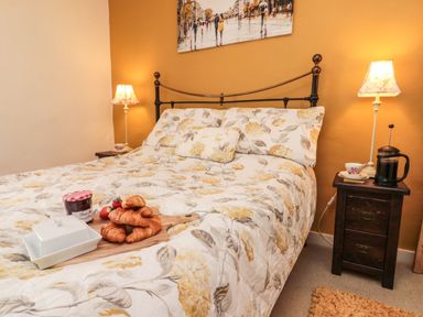A bedroom with a bed with floral bedding croissants on a wooden board and bedside tables with lamps at 12 Castlegate in Pickering