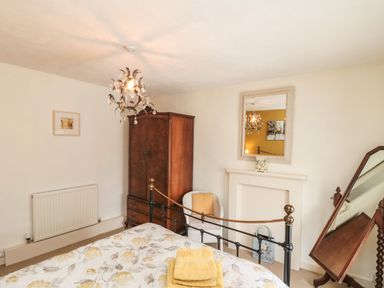 A bedroom with a bed a wooden wardrobe a white chair a wall mirror and a standing mirror at 12 Castlegate in Pickering