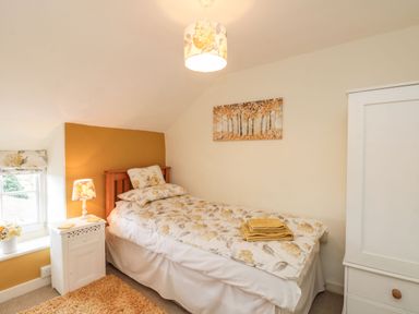 A bedroom with a single bed floral bedding bedside table with lamp and window at 12 Castlegate Pickering