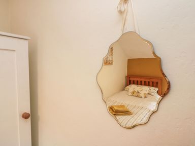 A bedroom with a bed reflected in a wall mirror and a white wardrobe on the left at 12 Castlegate in Pickering
