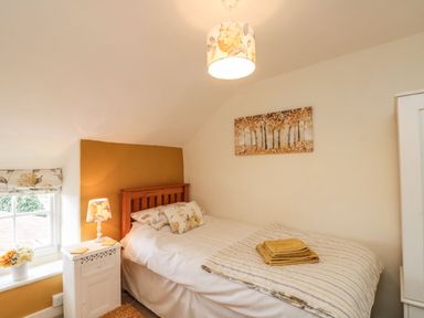 A bedroom with a single wooden bed and bedside table with a lamp at 12 Castlegate in Pickering