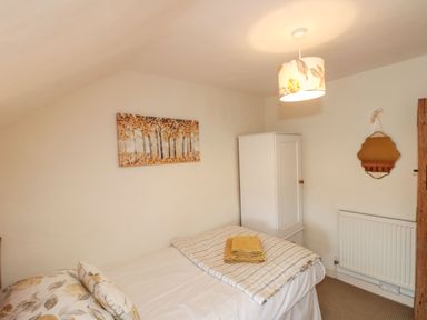 A bedroom with a single bed folded towels a white wardrobe a wall mirror and a radiator at 12 Castlegate in Pickering