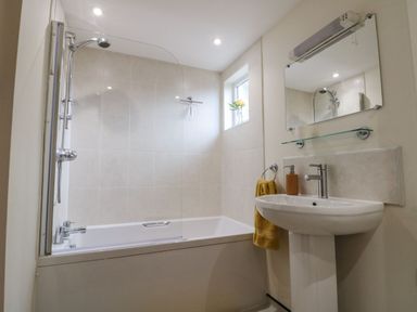A bathroom with a bathtub shower combination and a pedestal sink with mirror at 12 Castlegate in Pickering