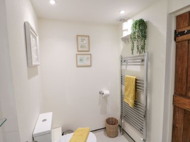 A bathroom with a toilet a towel rack yellow towels a wicker basket and framed pictures on the wall at 12 Castlegate in Pickering
