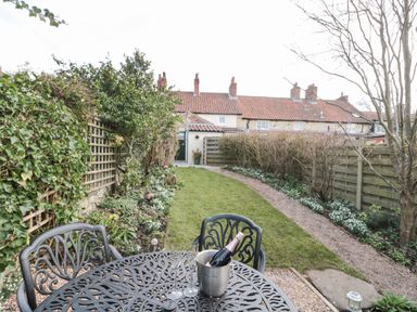 A garden with a black metal table and two chairs and a bottle in an ice bucket at 12 Castlegate in Pickering