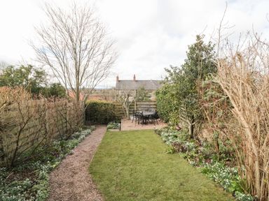 A small garden with a grass lawn a gravel path and a patio area with a table and chairs at 12 Castlegate in Pickering