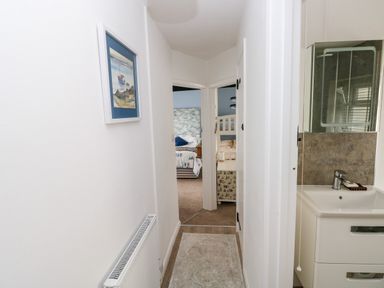 A hallway with a radiator and framed picture leading to bedrooms and a bathroom at Bluebell Cottage Jameston near Manorbier