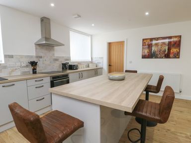 A kitchen with an island and brown chairs and appliances on the counter at The Church in Holyhead