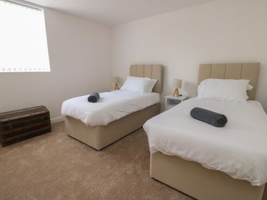 A bedroom with two single beds two bedside tables lamps and a wooden chest at The Church in Holyhead