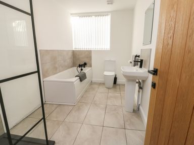 A bathroom with a bathtub toilet and sink with a wooden door at The Church in Holyhead