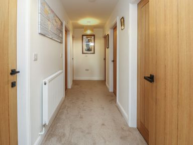 A carpeted hallway with wooden doors and a radiator on the wall at The Church in Holyhead