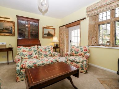 A sitting room with floral upholstered armchairs and a wooden coffee table at Ham cottage in East Lambrook near South Petherton