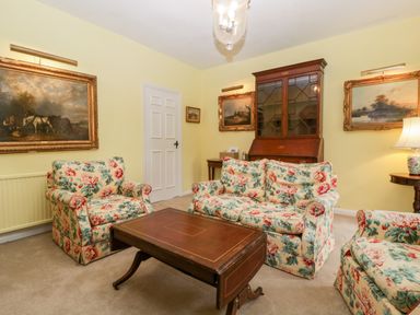 A sitting room with floral upholstered chairs and a wooden coffee table at Ham cottage in East Lambrook near South Petherton