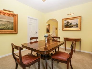 A dining room with a wooden table and four chairs paintings on the walls at Ham cottage in East Lambrook near South Petherton
