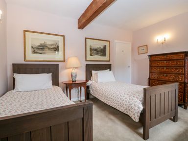 A bedroom with two single beds a bedside table with a lamp a wooden dresser and two framed pictures on the wall at Ham cottage East Lambrook near South Petherton