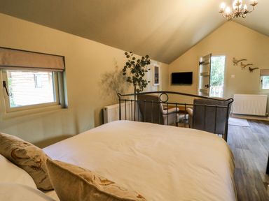 A bedroom with a bed facing two armchairs and a wall-mounted tv at Pheasant in Bedale