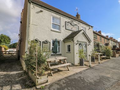 The exterior of a pub with picnic tables and plants outside at Pheasant in Bedale