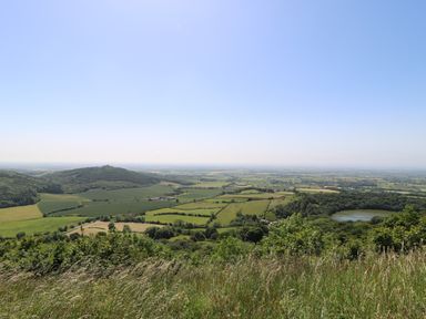 A landscape view of fields hills trees and a pond under a clear sky at Pheasant in Bedale