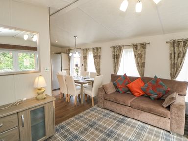 A living room and dining area with a sofa, dining table with chairs, and a cabinet with a lamp at Bock Retreat in Felton