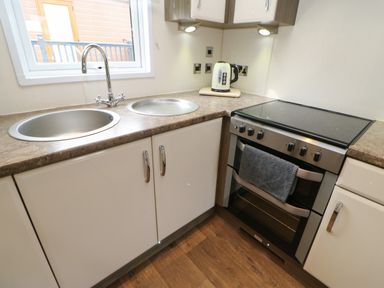 A kitchen corner with a double sink a kettle on the countertop and a stove with an oven at Bock Retreat in Felton