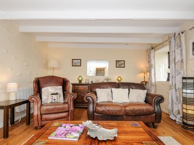 A living room with leather armchair and sofa wooden coffee table and side tables at Church View Cottage Near Looe