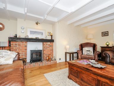 A living room with leather sofas a wooden coffee table a brick fireplace and a wooden floor at Church View Cottage Near Looe