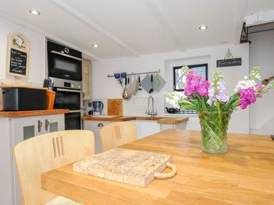 A kitchen with wooden countertops a vase of flowers on the table and built in ovens at Church View Cottage Near Looe