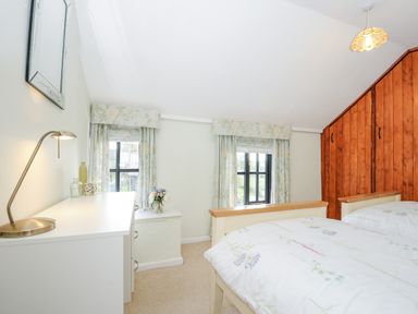 A bedroom with two single beds white dresser and floral curtains at Church View Cottage Near Looe