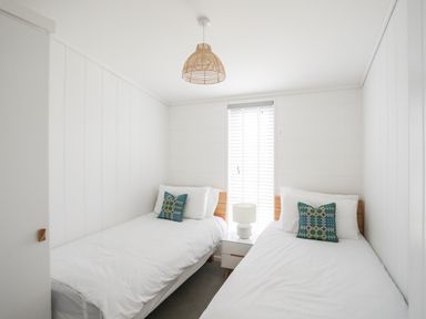 A bedroom with two single beds a nightstand and a lamp at Galwad y Mor in Niwbwrch newborough