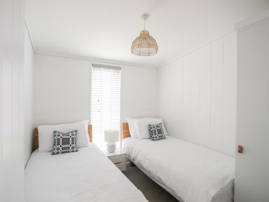 A bedroom with two single beds a bedside table and a lamp at Galwad y Mor in Niwbwrch newborough