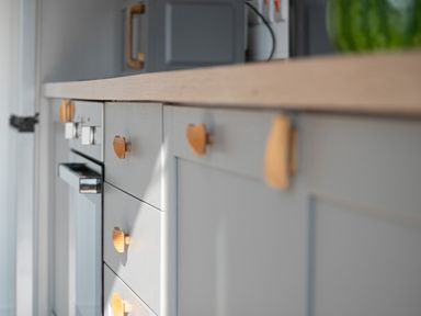 A kitchen counter with gray cabinets and wooden handles with an oven below the counter at Galwad y Mor in Niwbwrch newborough