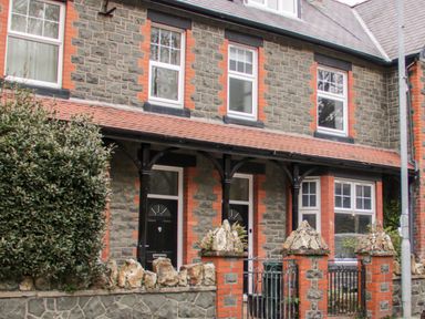Stone brick terraced houses with black doors and windows behind a low stone wall and gate at Gwyder in Penmaenmawr
