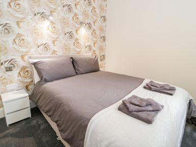 A bedroom with a double bed gray bedding and towels on a white blanket at Gwyder in Penmaenmawr