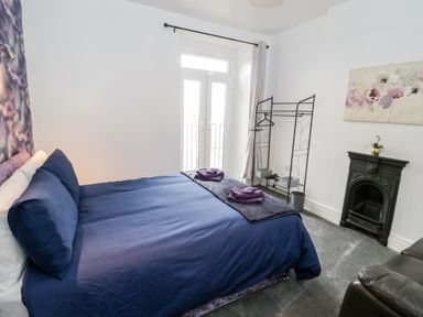 A bedroom with a double bed beside a window a fireplace and a clothes rack at Gwyder in Penmaenmawr