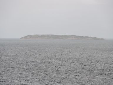 An island in the distance surrounded by water with a cloudy sky at Gwyder in Penmaenmawr