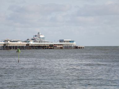 A pier with buildings extending over the sea under a cloudy sky at Gwyder in Penmaenmawr