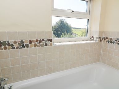 A bathroom with a bath tub and window at Wayside near Kingsbridge
