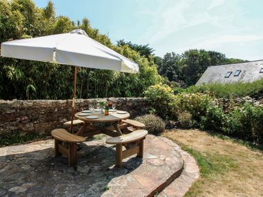 A table and chairs under an umbrella in the garden at Wayside near Kingsbridge