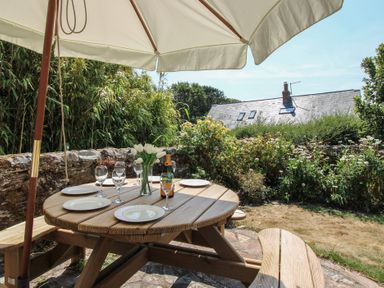A table with glasses and a bottle under an umbrella at Wayside near Kingsbridge