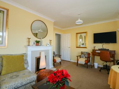 A living room with a fireplace a sofa a desk with a chair and a wall mounted television at See The Sea in Hunstanton