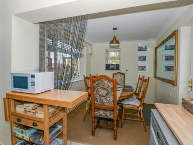 A dining room with a wooden table and chairs a microwave on a wooden cart and a large mirror on the wall at See The Sea in Hunstanton