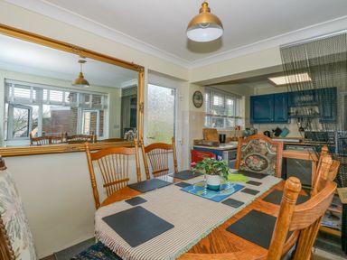 A dining area with a wooden table and chairs next to a kitchen with blue cabinets at See The Sea in Hunstanton