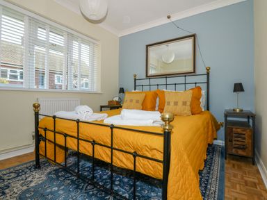 A bedroom with a black metal bed frame and mustard yellow bedding at See The Sea in Hunstanton