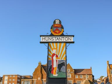 A sign with a crowned figure and a dog with buildings in the background at See The Sea in Hunstanton