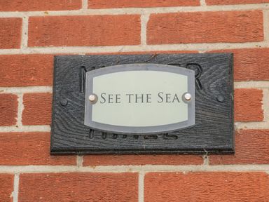 A nameplate on a brick wall with the text See The Sea at See The Sea in Hunstanton