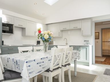 A kitchen with a dining table and chairs with flowers on the table at Lambley View in Bude