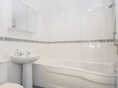 A bathroom with a bathtub shower and sink with mirror cabinet at Lambley View in Bude